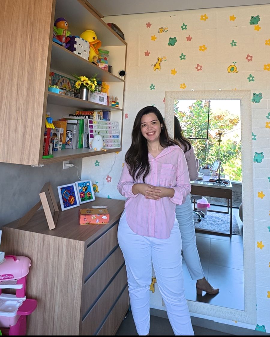 Letícia na sala de atendimento, com estante de brinquedos e parede decorada